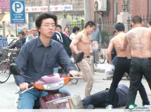 Three Chinese hoodlums/gangsters kicking someone in the street.