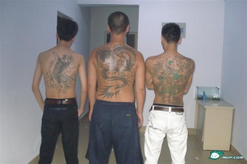 Three Chinese gang members showing off their tattoos.