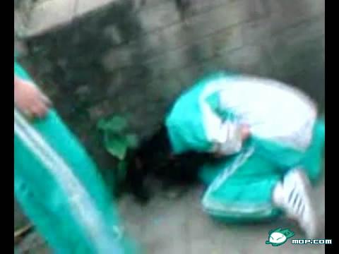 A screen capture of a video where a Cantonese girl in a school uniform is bent over after being beaten by her classmates for stealing.