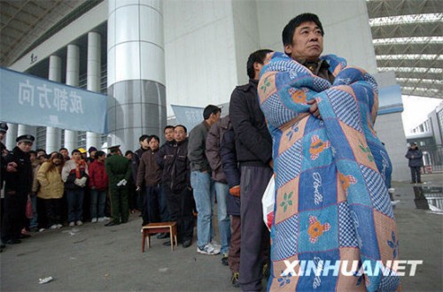 1月2日，在宁波国际会展中心临时售票点，一名排了两天队的购票者披着棉被等待买票。新华社发