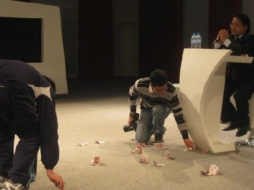 Organizers help clean up the 50 cent cash notes thrown by a student protesting the propaganda official's speech at Remin University.