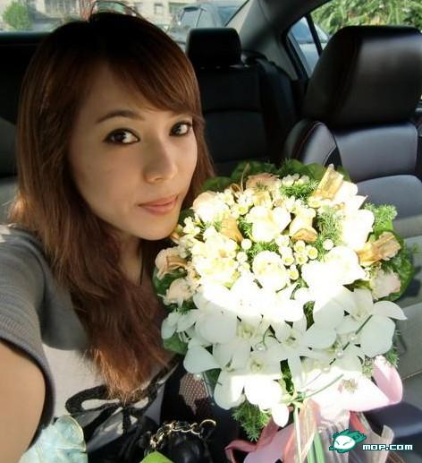 Chinese girl holding a bouquet of flowers inside a car.