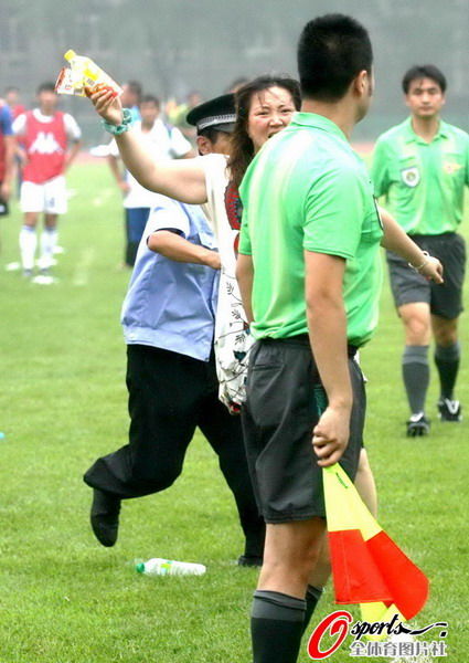 An angry female fan at a football  game in Dalian, China chases and attacks a referee.