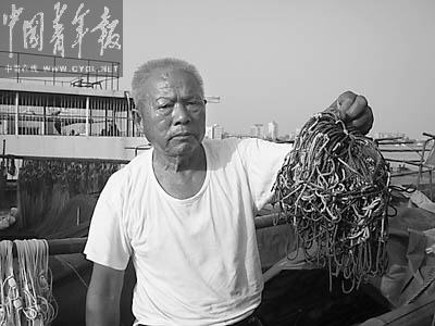 Wang Shouhai, the fisherman condemned by China's public for refusing to recover the bodies of drowned students unless paid is shown here holding the hooks he used to dredge the river for bodies.