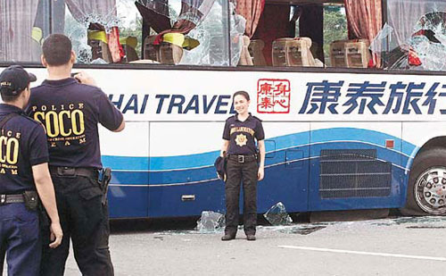 A policewoman takes a photo in front of the disabled Hong Kong tour bus that was involved in a hostage crisis.