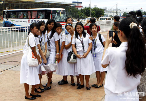 Philippine schoolgirls taking a group photo in front of the disabled Hong Kong tour bus that was involved in a hostage crisis.
