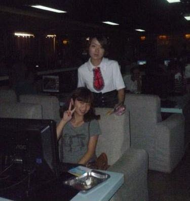 A female customer also taking a photo with the "school uniform" wearing service staff at this Chinese internet bar.