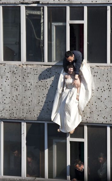 A local government official with his arms around a girl in a wedding dress who had just jumped from the 7th floor.