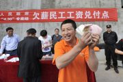 A happy Chinese migrant worker in Chongqing holding up the overdue wages he has finally been paid.