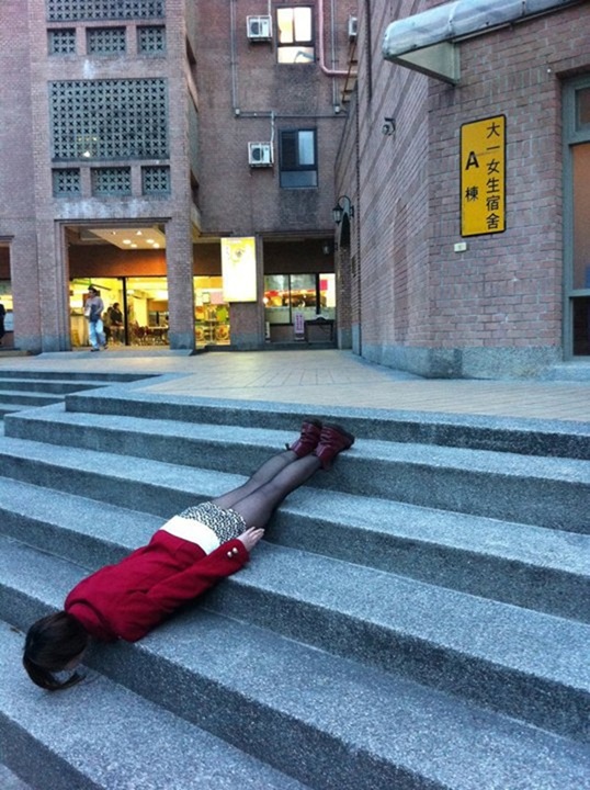 A young girl in Taiwan lies face down over some steps.