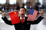 A boy who is waiting to greet U.S. Secretary of State Hillary Clinton at the National Museum makes a face while holding the U.S. and Chinese flags in Beijing May 4, 2012. REUTERS/Shannon Stapleton