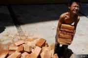 A young Chinese boy carrying bricks.